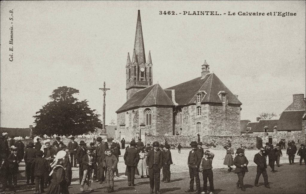 Le calvaire et l'église Saint-Pierre dans le bourg de Plaintel au début des années 1900.